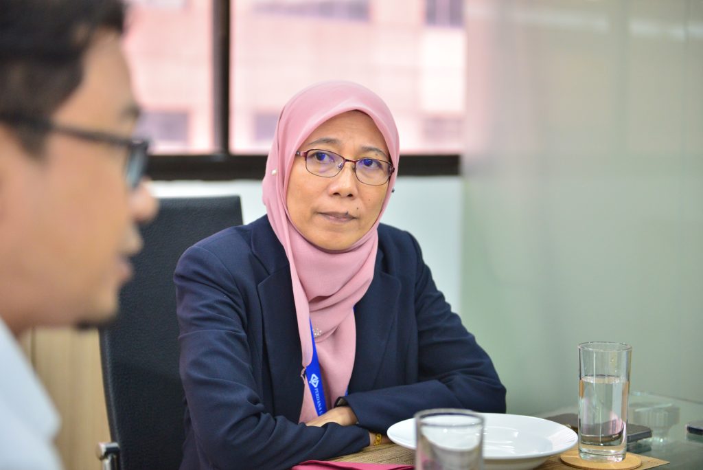 a woman in a pink scarf sitting at a table with a man in glasses